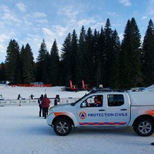 Photographie du VLHR posant devant l'écriteau de la Transjurassienne dans la neige